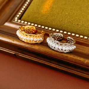 Close-up of gold and silver plated open rings with pearls on vintage wood frame