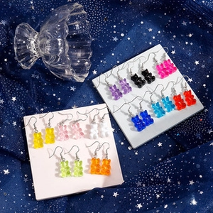 Detailed view of colorful gummy bear earrings in resin on starry blue background