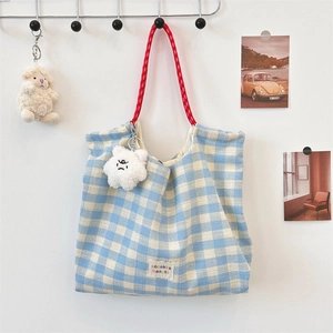 Detail of blue plaid tote bag with red rope handle and plush cloud charm accessory