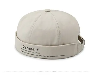 Detail of beige brimless docker cap featuring side embroidery and adjustable metal strap