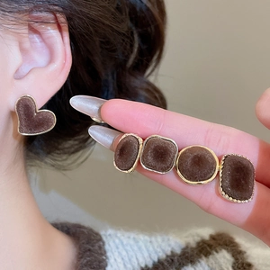 Close-up of brown velvet geometric stud earrings with gold edges on a model's ear