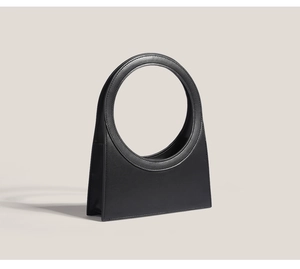 Minimalist black leather handbag featuring a unique circular cutout handle design