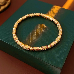Detail view of 18k gold plated bracelet with pink zircon cylinders on a luxury jewelry box