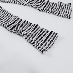 Détail macro du pantalon en maille rayée avec tissu texturé et bordures effilochées