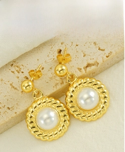 Dettaglio macro di orecchini a perla vintage francesi su pietra di travertino beige