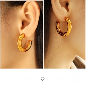Detailed view of textured golden C-shaped hoop earrings with vertical and hammered patterns