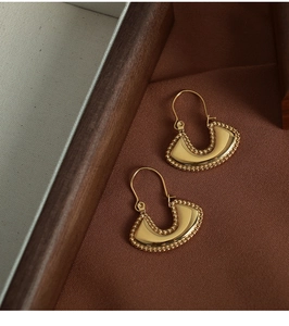 Detailed close-up of vintage gold saddle-shaped earrings with fine beaded edge craftsmanship