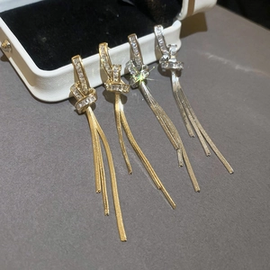 Detail of knotted gold and silver tassel earrings with square-cut cubic zirconia crystals