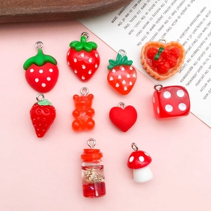 Flat lay of red resin charms featuring strawberry, mushroom, and heart shapes for DIY jewelry
