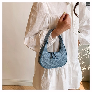 Close-up of blue woven texture and crescent shape on a stylish underarm handbag