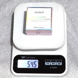 Vue macro du poudrier 3 couleurs sur balance affichant un poids de 54,5g de produit