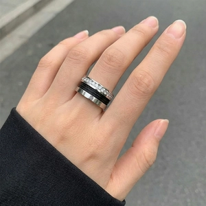 Detail of multi-layer ring featuring a sparkling diamond row and black woven texture