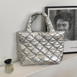Detail of silver metallic puffer tote bag with diamond quilted pattern and thick handle