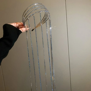 Detailed view of silver crystal headband with blue fringe tassels held in hand
