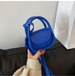 Détail du mini sac bandoulière bleu Klein avec poignée ronde et texture cuir mat