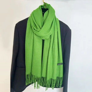 Detailed texture of bright green cashmere scarf with fringe hanging on a dark suit