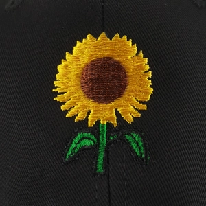 Detailed macro shot of a vibrant yellow sunflower embroidery on a black cotton baseball cap
