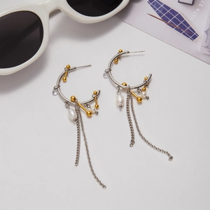 Macro detail of stainless steel C-shape earrings with pearls and long tassel chains