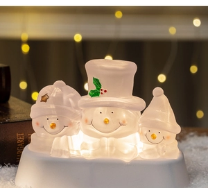 Close-up of a glowing snowman family trio with warm bokeh lights and festive holiday decor