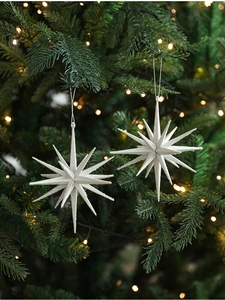 Close-up of white glittery star ornaments with silver strings hanging on a Christmas tree