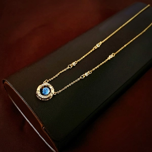 Détail d'un collier géométrique doré avec pendentif en cristal bleu et pavé de pierres