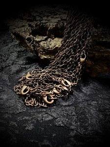 Close-up of vintage bronze metal chains and clasps on a dark textured wood background