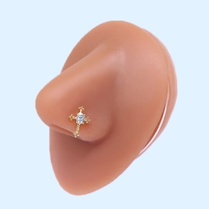 Gold stainless steel cross nose stud with clear zircon stone on blue background