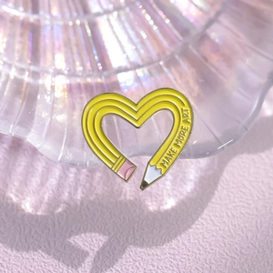 Cartoon heart-shaped pencil enamel brooch with Make More Art text on yellow body