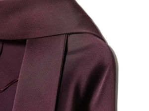 Detaillierte Nahaufnahme der glatten Satinstruktur und Schulternaht am burgunderroten Kleid