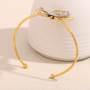 Detail of 18K gold-plated bangle featuring a layered silver bow and heart design