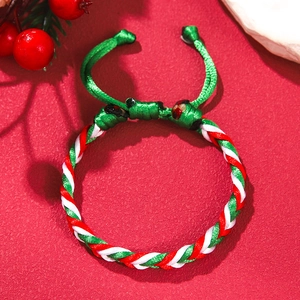 Close-up of a woven Christmas bracelet in red and green with an adjustable knot