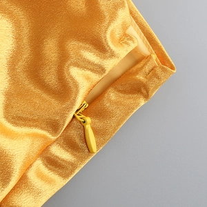 Vue détaillée d'une fermeture éclair invisible sur le tissu en satin doré d'une robe de soirée