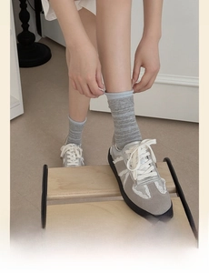 Detail of grey striped socks with blue trim paired with silver lace-up shoes