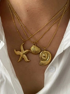 Detailed view of layered gold starfish shell and nautilus pendant necklaces on model