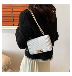 Detail of white chevron leather bag with gold chain strap and metallic lock on model