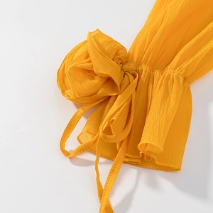 Detailed close-up of yellow ruffled cuffs with delicate tie-knot and pleated texture