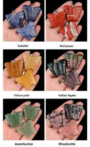 Detail showing various butterfly pendants in natural stones held to show scale and texture