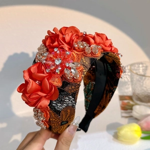 Detailed close-up of handmade orange fabric flowers and sparkling rhinestones on the headband