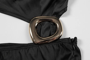 Detail of sleek black fabric featuring a gold metal ring and hidden zipper closure