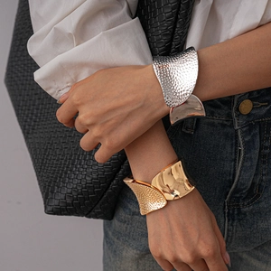 Irregular hammered metal cuff bracelet worn by model on arm with clean grey background