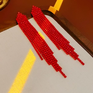 Macro shot of red tassel earrings with sparkling rhinestones on a wooden tray