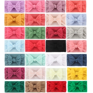 Flat lay of 28 assorted colors of soft nylon baby headbands with large bows in a grid