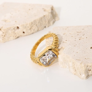 Detailed macro view of a gold croissant twisted ring featuring a large emerald cut zircon