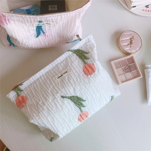 Détail d'une trousse à maquillage en seersucker brodée de tulipes avec fermeture éclair