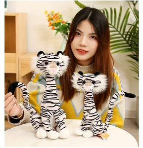 Detail of soft white tiger plush toys with black stripes held by a person in a cozy room
