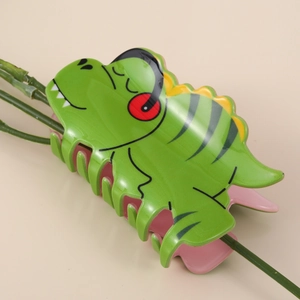 Cute green dinosaur acetate hair claw clip with pink interior on a beige background