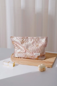 Close-up of floral jacquard fabric and brand label on a premium travel cosmetic pouch
