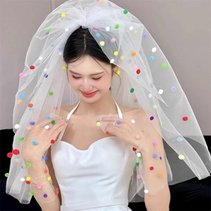 Detail of multi-colored plush pom-poms on a fluffy white layered tulle wedding veil