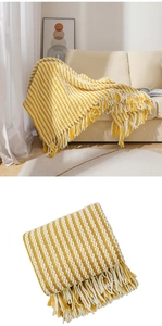 Detail of yellow and white striped knit throw blanket with decorative tassels on sofa