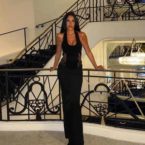 Longue robe noire licou avec dentelle ajourée posée sur un escalier en colimaçon de luxe